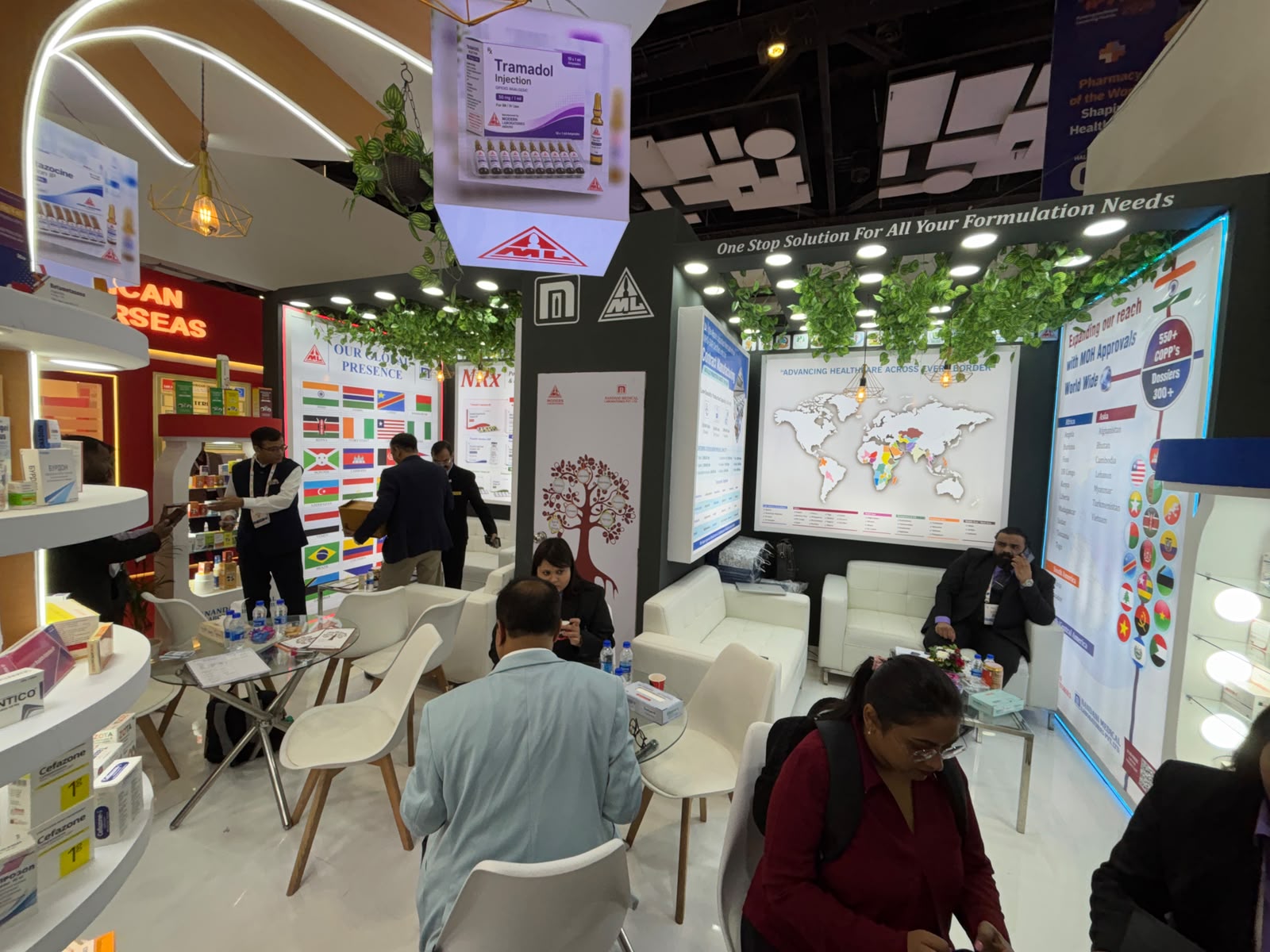 Nandani Medical Laboratories stall interior at iPhex 2026 — formulation headwall, global-presence flag wall, world map graphic and visitor seating
