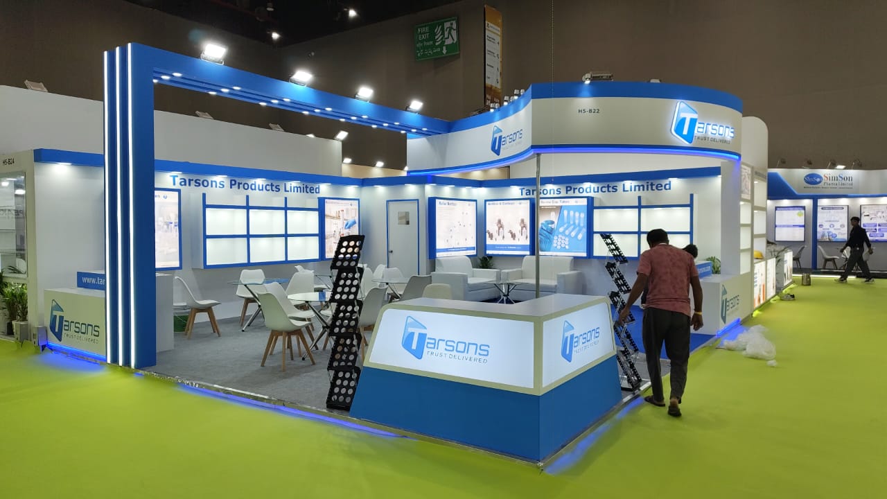 Tarsons Products Limited exhibition stall at Analytica 2026 — wide front view with the illuminated blue portal frame and reception counter